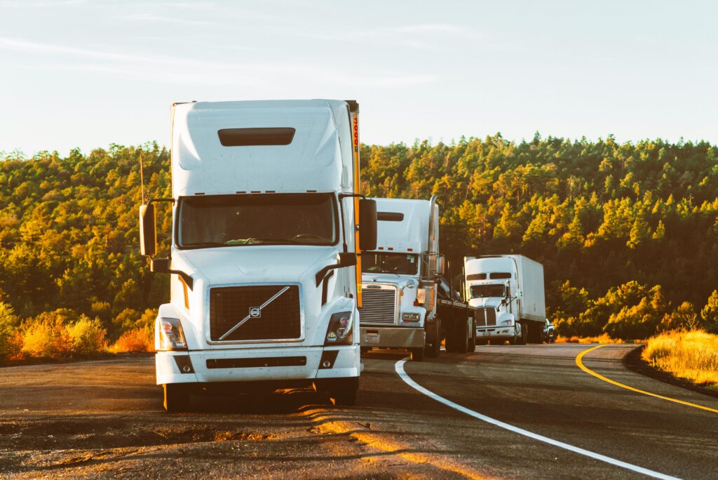 pexels-photo-2199293-2199293 Three semi trucks driving on a highway through a forested landscape in Arizona.